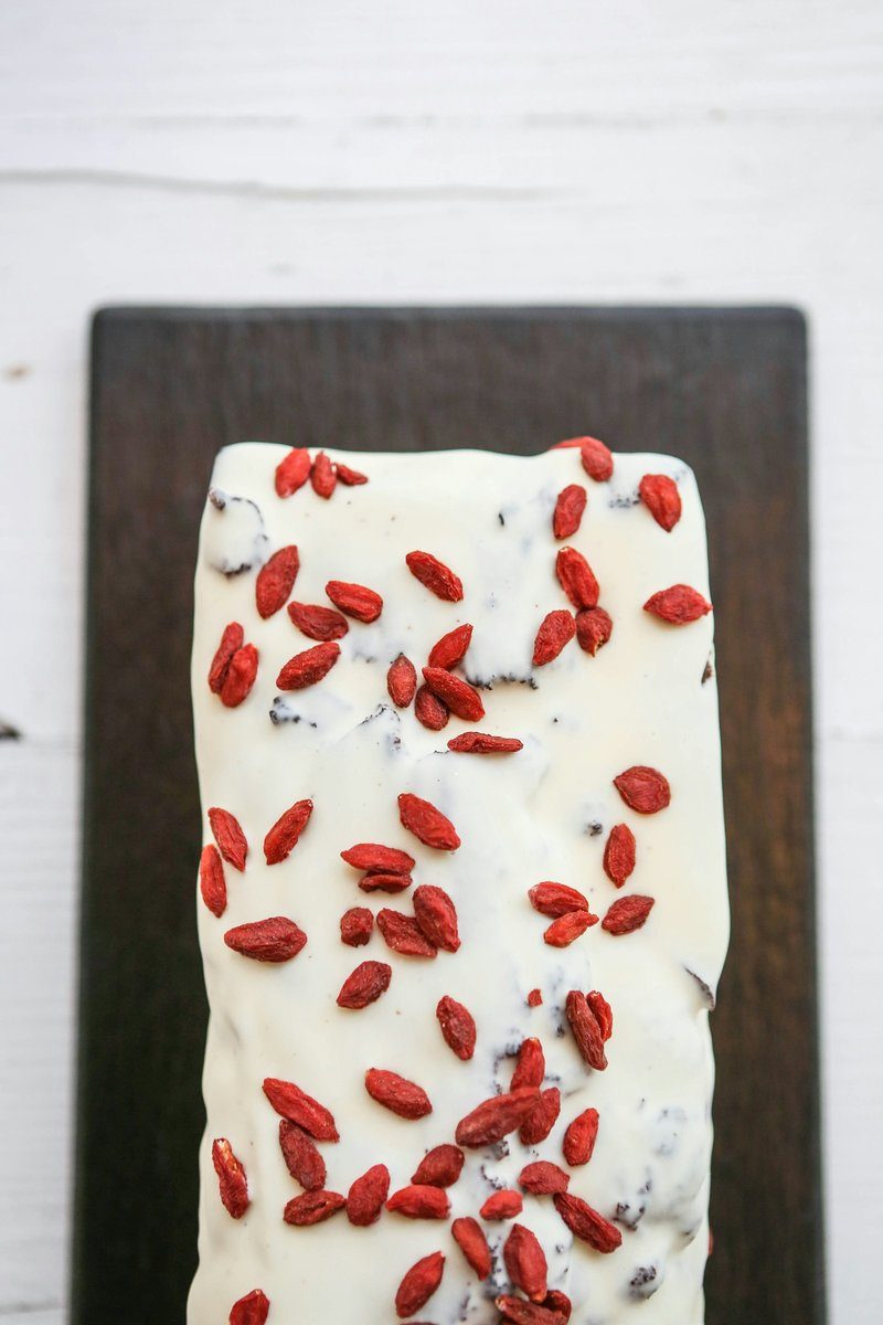 Part de gâteau au glaçage blanc parsemée de baies de goji